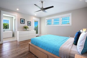 Een slaapkamer met een bed, een plafondventilator, een dressoir en een raam met jaloezieën.