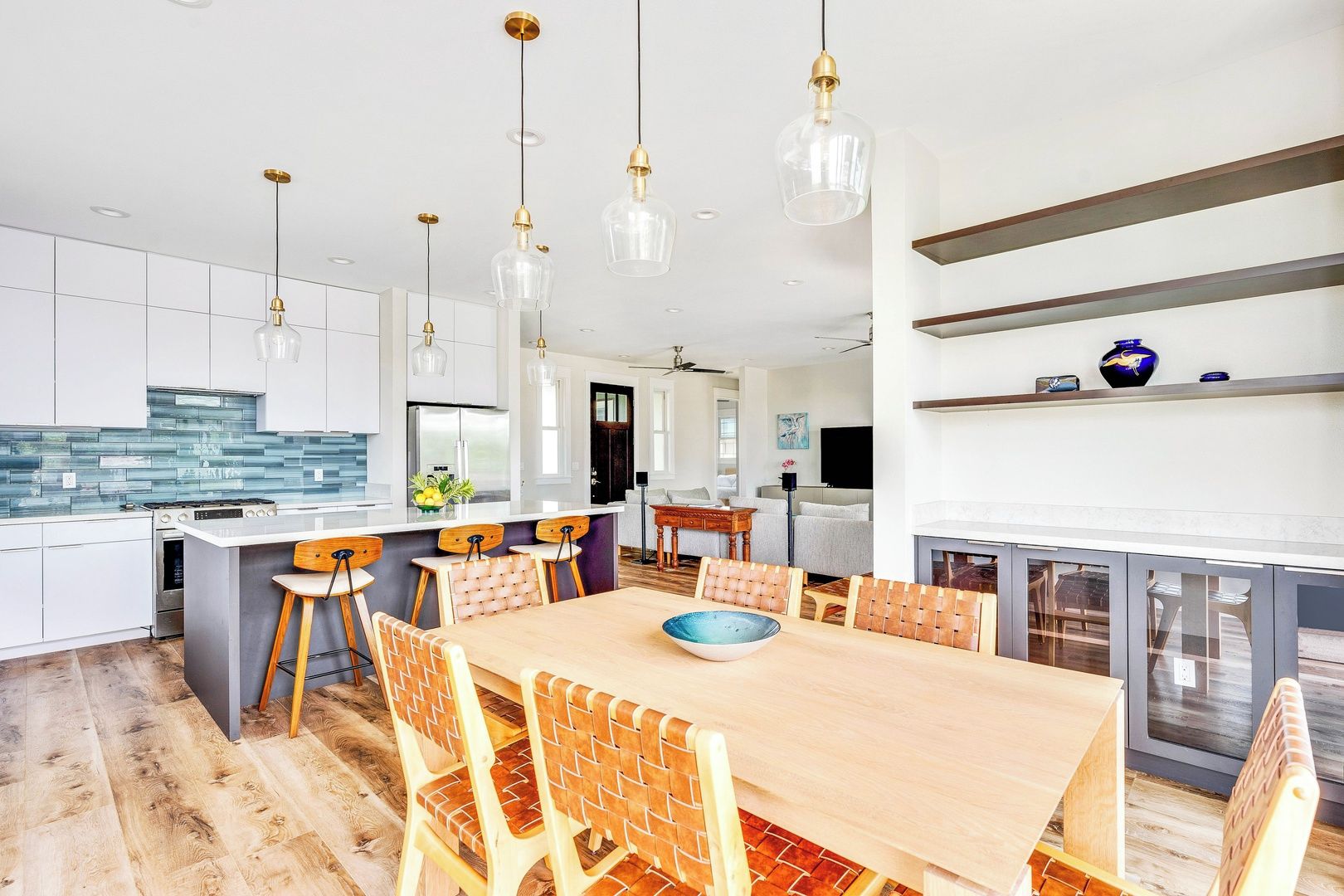 Una cocina moderna con armarios blancos, una isla central e iluminación colgante.