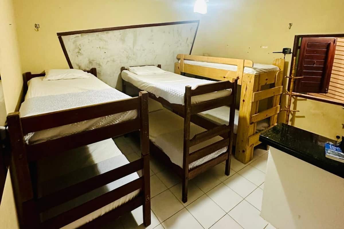 Um dormitório com beliches, ventilador de teto e piso ladrilhado.