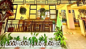 A spacious atrium with a high ceiling, wooden beams, and a central seating area with a railing. - Papierus Pensionne (Kalibo)
