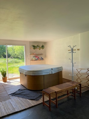 Un baño moderno con una bañera independiente, bancos de madera, un tendedero y estantes con plantas.