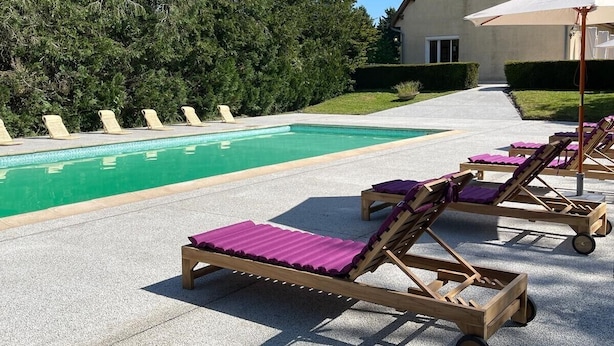 A poolside area with lounge chairs and a house in the background. - Villa Bien-être et Fête : Jacuzzi, Sauna, Court de Tennis, Piscine D'été, Étang (Cézy)