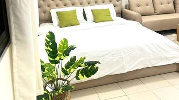 A bedroom with a large bed, a beige sofa, and a wall-mounted light fixture.