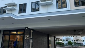 A modern building with a flat facade, multiple balconies, and a ground-level entrance with a glass door. - Hill Residence by Sarah Rentals (Caloocan)