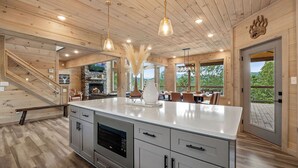 A spacious kitchen with a large island, wooden ceiling, and modern appliances.