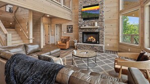 A spacious living room with a fireplace, leather sofas, a coffee table, and a stone accent wall.