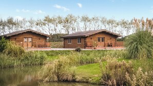 Un bâtiment de style cabane en bois, doté d’un porche et d’un petit étang à l’avant.