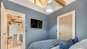 Een slaapkamer met een bed, een televisie en een deur.