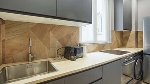 Une cuisine moderne dotée d’un évier en acier inoxydable, d’un grille-pain et d’un four encastré.
