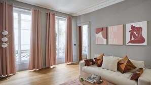 Un salon moderne avec un canapé, une table basse et des œuvres d’art accrochées au mur.