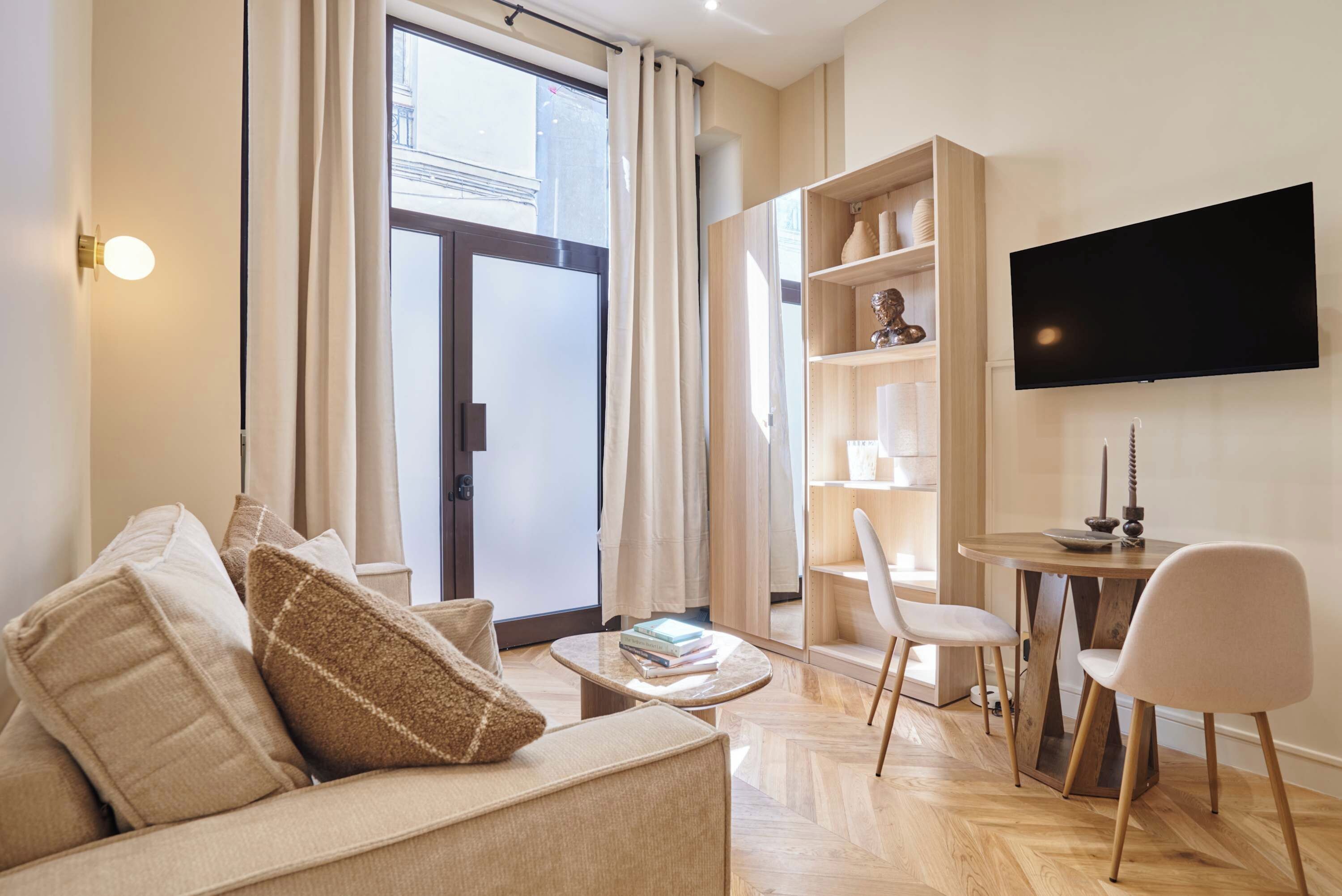 A modern living room with a sofa, a coffee table, a bookshelf, a TV, and a dining area.