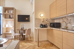 A compact kitchen with a dining area, a flat-screen TV, and a coffee maker.