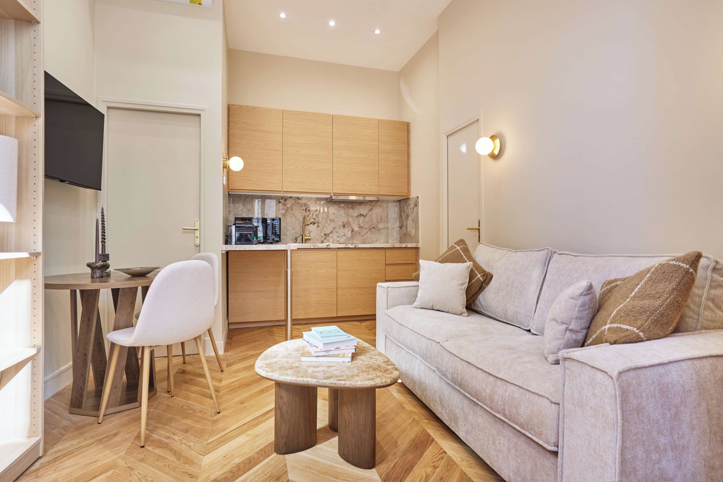 Een ruimtelijke zithoek met een kitchenette, een bank, een eettafel en een stoel.