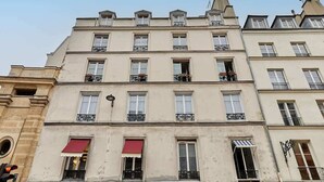 A multi-story building with a classic architectural style, featuring balconies and windows with awnings. - Cosi apartment Bastille-Le Marais (Paris)