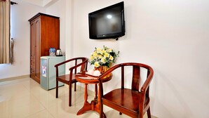 A dining area with a table, chairs, a TV mounted on the wall, a refrigerator, and a cabinet.