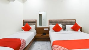 Ein Hotelzimmer mit zwei Betten, einem Nachttisch, einem Spiegel und einer Klimaanlage.