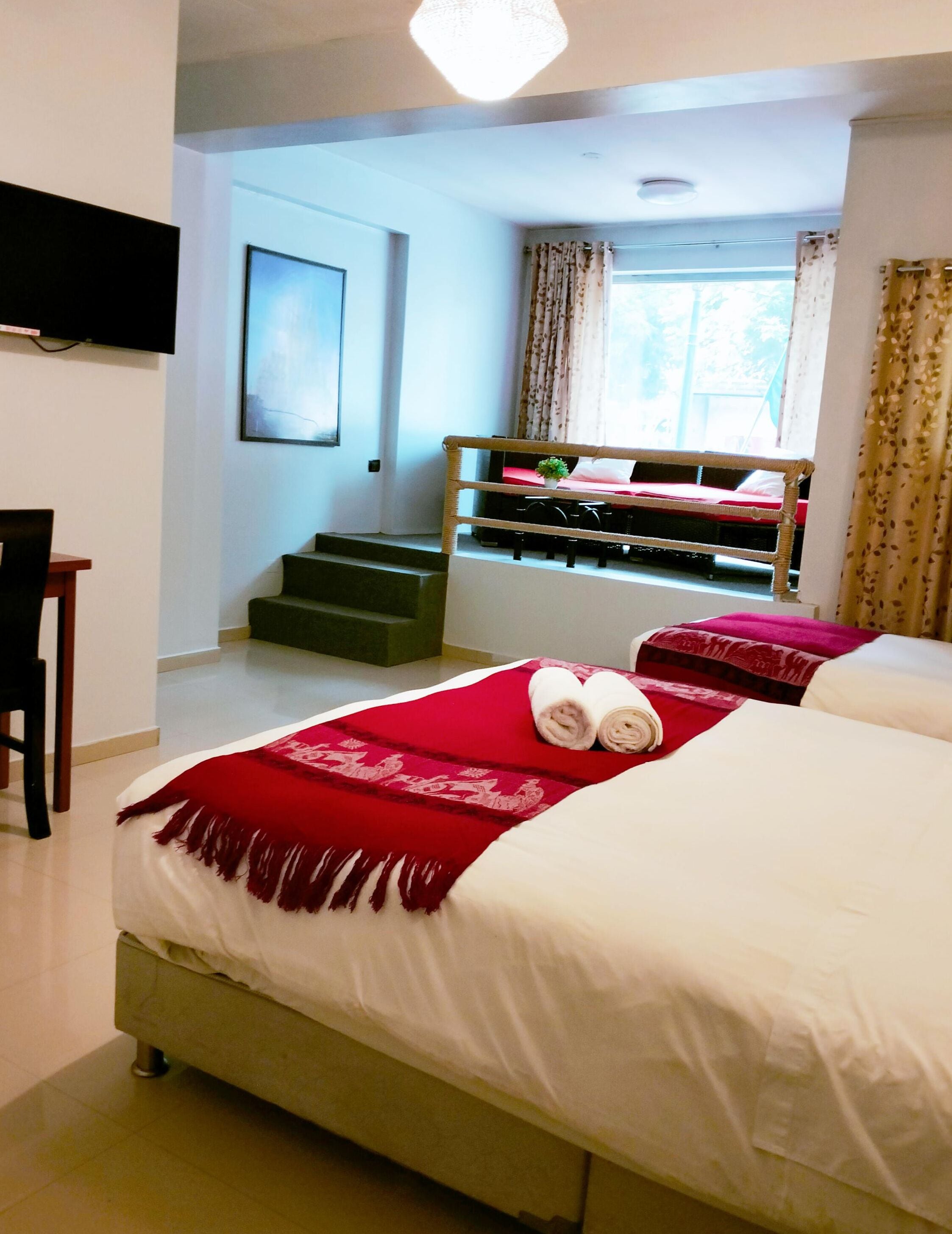 A hotel room with a bed, a desk, and a window with curtains.