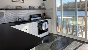 Une cuisine moderne avec un plan de travail noir, des armoires blanches et une grande fenêtre donnant sur un lac.