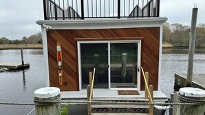 Un petit quai en bois, doté d’une rambarde métallique et agrémenté d’une plante en pot.