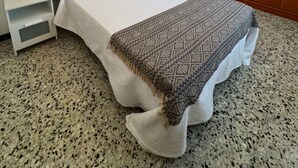 Un dormitorio con una cama, una mesita de noche, una lámpara, un armario de madera y un candelabro.