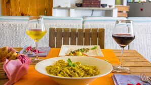 A dining table with a bowl of pasta, two glasses of wine, and a plate of food. - Arganama (San Jose)