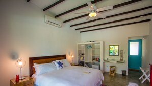A bedroom with a bed, bedside tables, a wardrobe, a mirror, and a ceiling fan. - Arganama (San Jose)