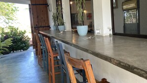 A bar area with wooden chairs and potted plants. - Arganama (San Jose)