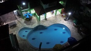 A swimming pool with multiple lanes and a small kiddie pool, surrounded by a covered area with seating and umbrellas. - Pousada Samburá (Ipojuca)