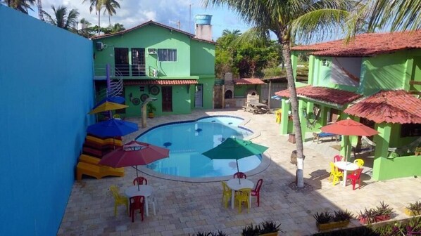 A pool area with a circular pool, outdoor seating, and colorful umbrellas. - Pousada Samburá (Ipojuca)