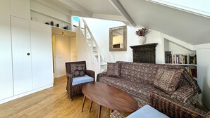 Ein geräumiges Loft mit hohen Decken, einer Treppe, einem großen Sofa, einem Esstisch und einem Bücherregal.