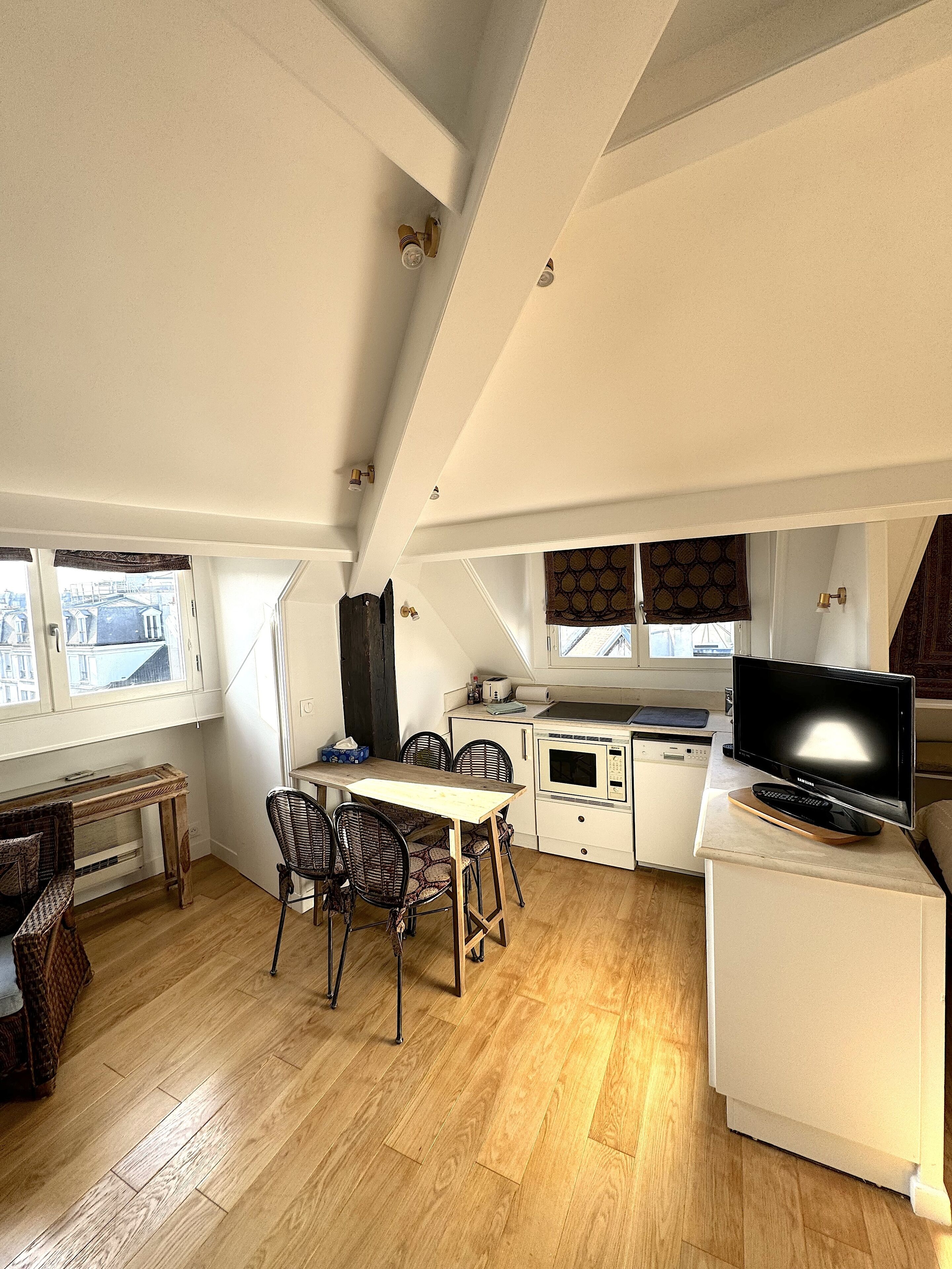 A compact kitchen with a dining area, a microwave, a toaster, and a television.
