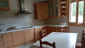 Una cocina con armarios de madera, salpicadero de azulejos, ventana con vistas y una mesa con sillas.