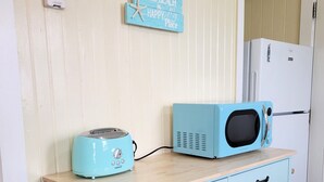 Eine Küchenzeile mit einer blauen Mikrowelle, einem Toaster und einer Holzausziehtheke.