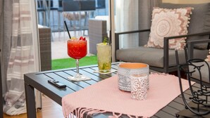 Une table avec deux boissons, une bougie décorée et une couverture dans une pièce avec vue.