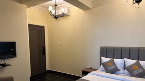 Ein Hotelzimmer mit Bett, Fernseher, einer Kristallleuchtre und einer Tür.