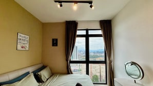 A hotel room with a bed, a bedside table with a mirror, a window with curtains, and a view of the cityscape. - Neu Suites by Moonlight  (Kuala Lumpur)