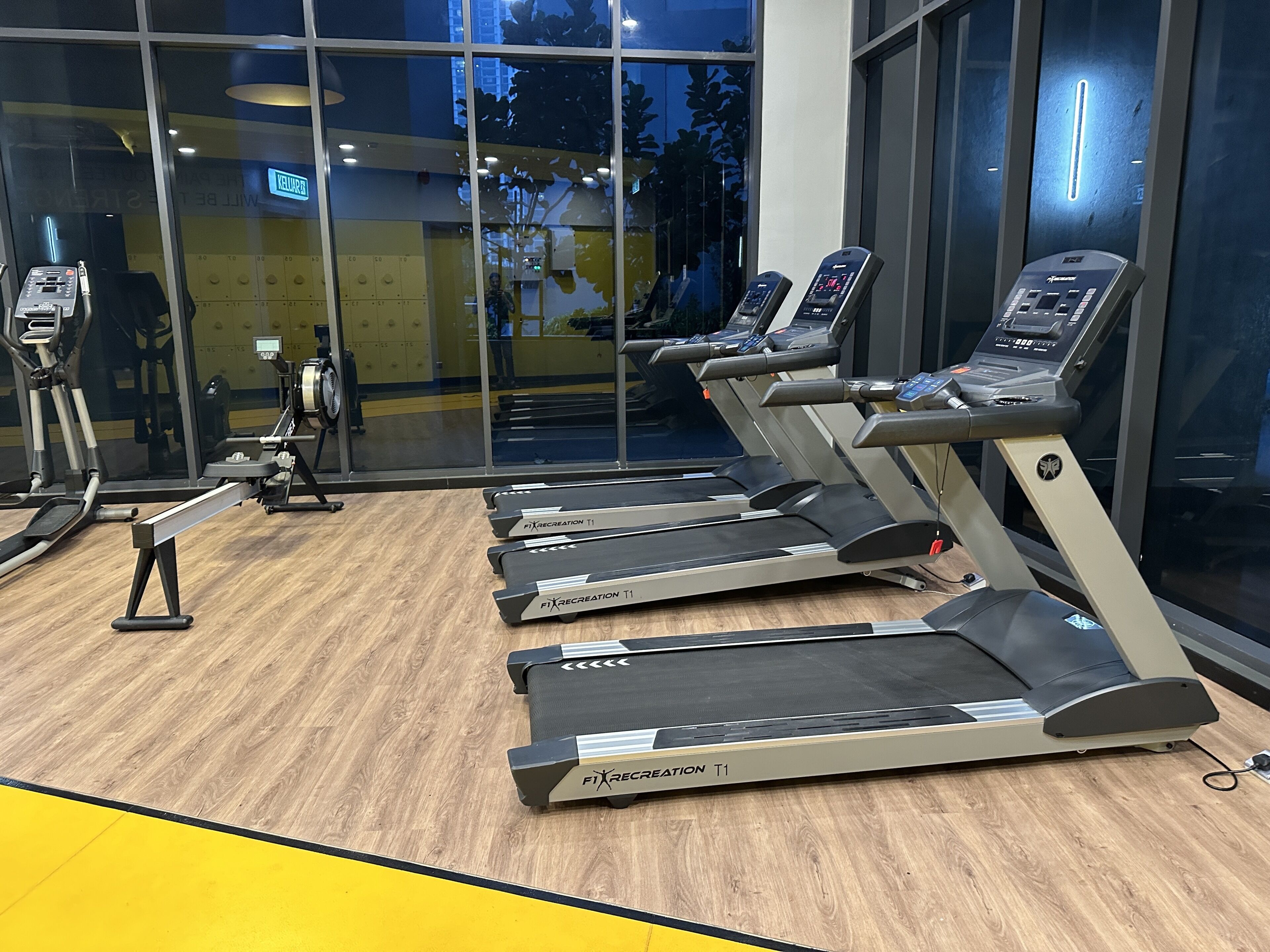 Ein Fitnessstudio mit Laufbändern, Trainingsgeräten und Holzboden.