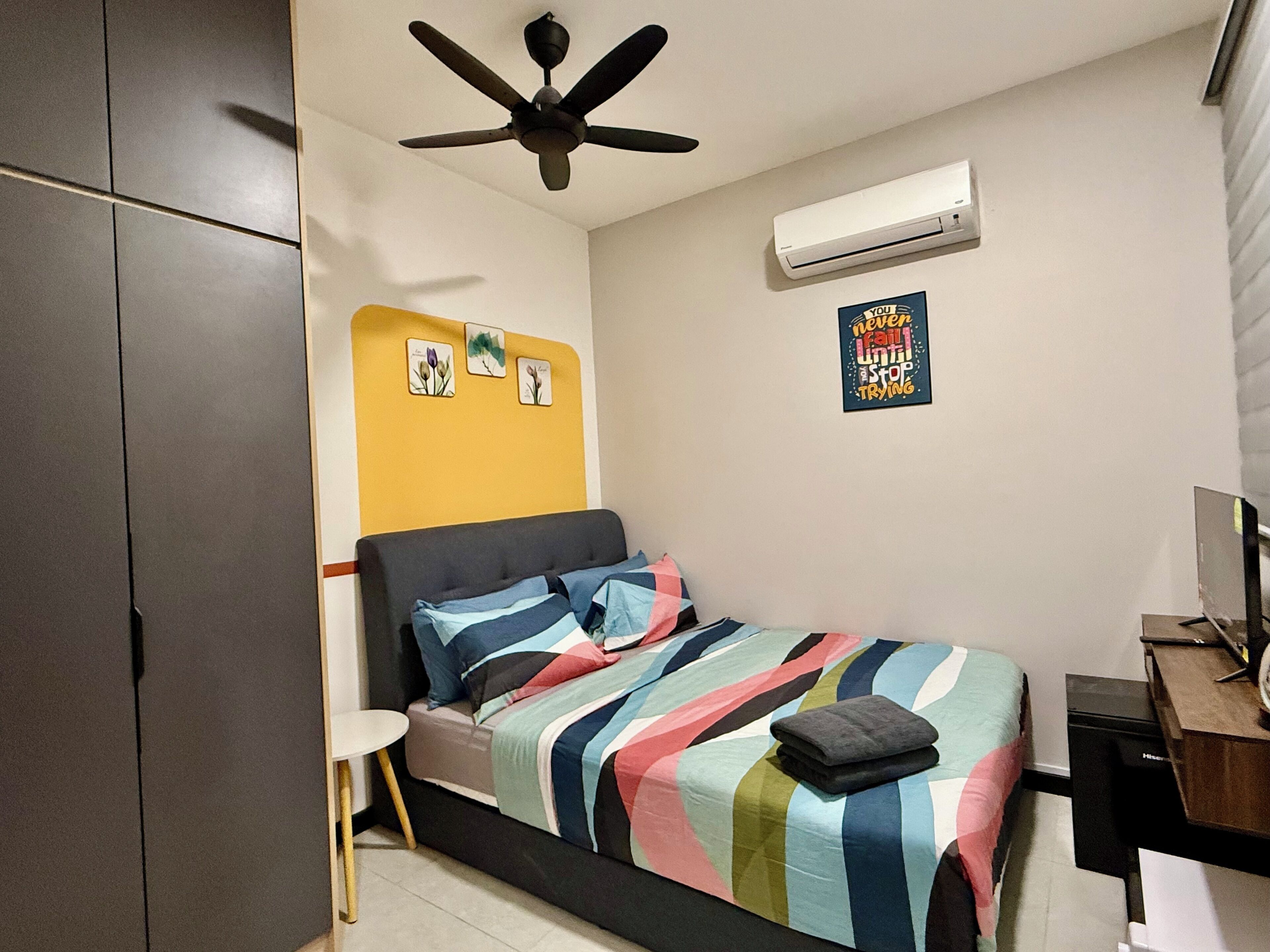 Een slaapkamer met een bed, een plafondventilator, een airconditioner en een motiverende poster aan de muur.