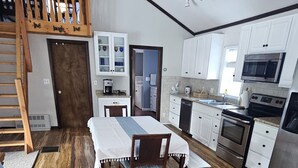 A spacious kitchen with white cabinets, a wooden dining table, and a built-in microwave. - Cozy Lake Front home for Boating, fishing, winter sports, and gorgeous views,  (Errol)
