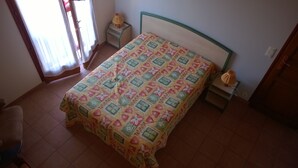Um quarto com uma cama, uma mesa de cabeceira, um abajur e uma cadeira.