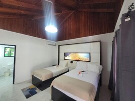Una habitación con dos camas, un televisor montado en la pared y techo de madera.