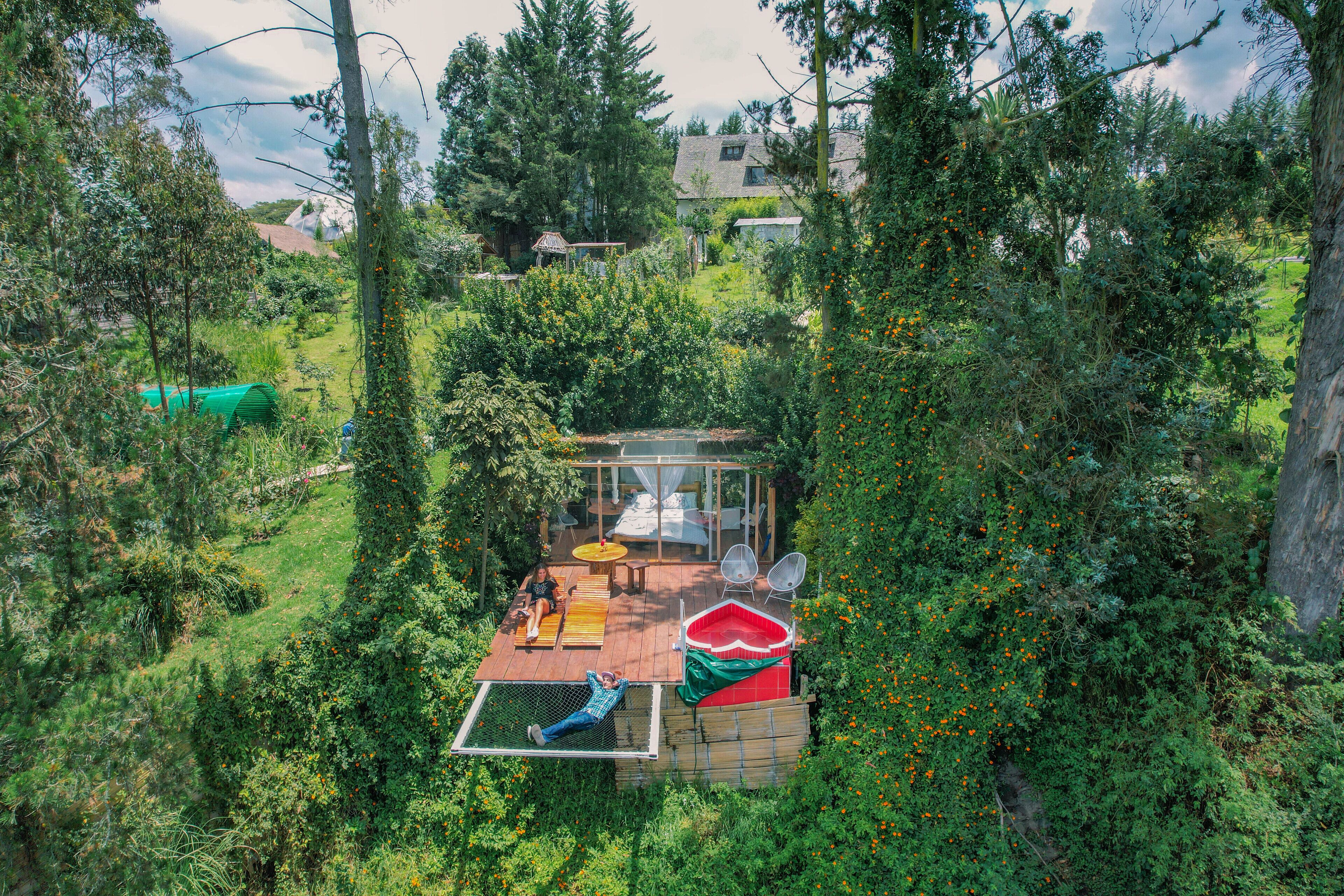 A secluded outdoor deck with a glass enclosure, a hot tub, and a hammock.