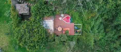 Vista aérea de una casa con terraza de madera, rodeada de abundante vegetación.