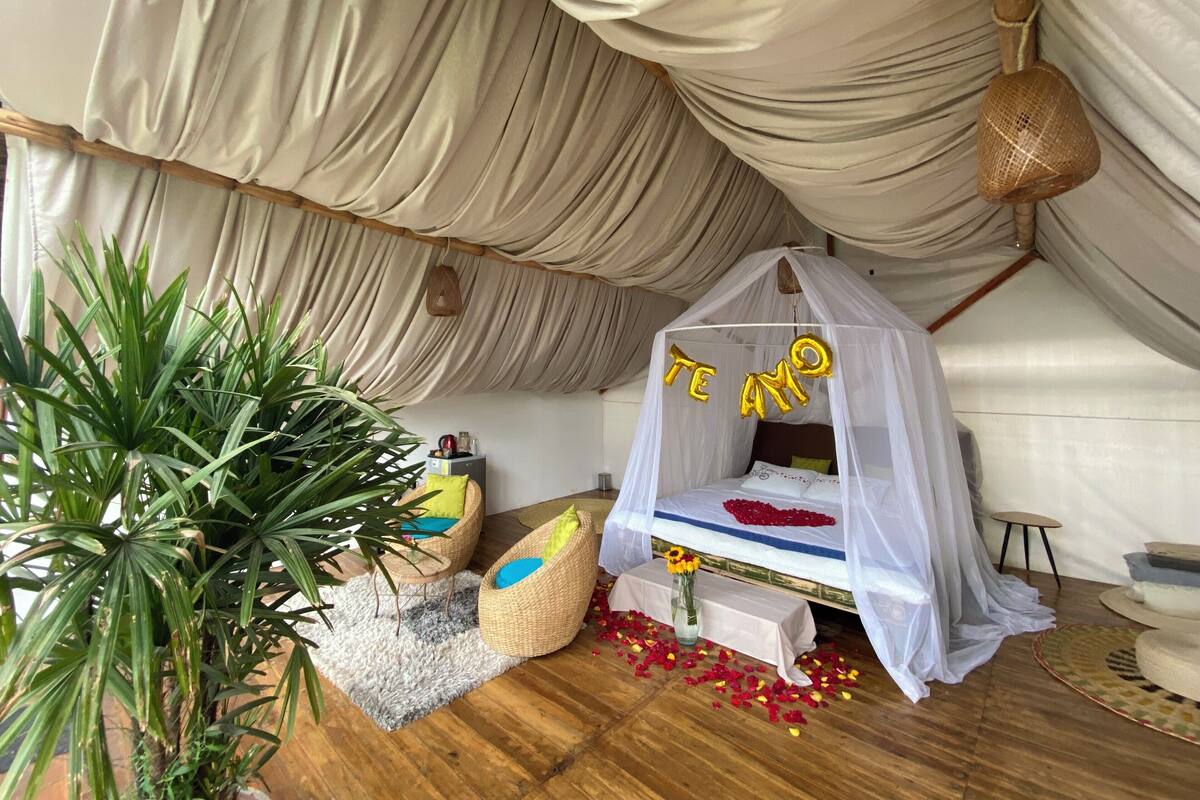 A cozy room with a canopy bed, a large potted plant, and a small table with a vase of flowers.