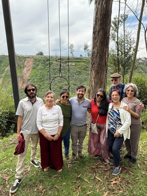 A group of people standing on a grassy area with a tree and a swing set in the background.
