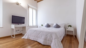 A bedroom with a bed, a television on a desk, and a window. - Dimora Piazza Martiri | A/C WiFi FS Station-Center (Carpi)