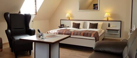 A hotel room with a bed, two bedside tables, a desk, two chairs, a mirror, and a window.