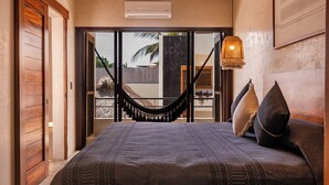 Un dormitorio con una cama grande, una hamaca y vistas al exterior.