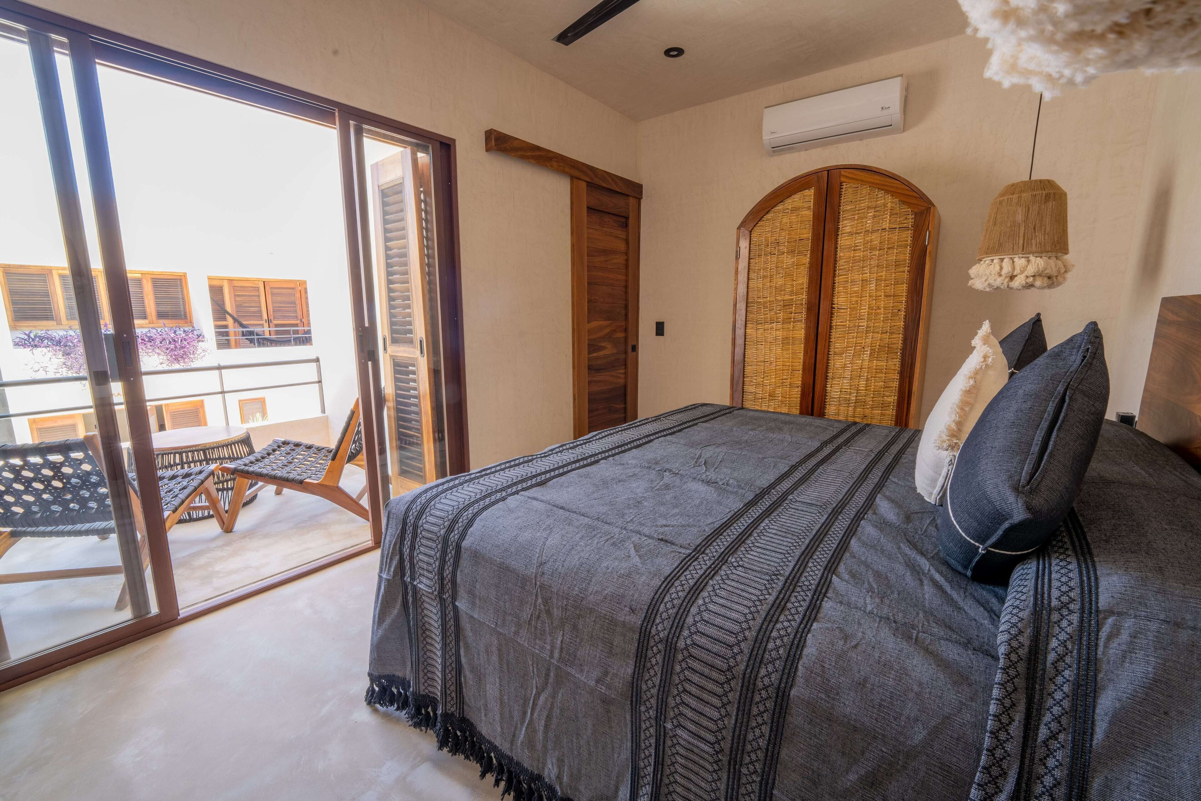 A bedroom with a large bed, a sliding glass door leading to a balcony, and a woven headboard.
