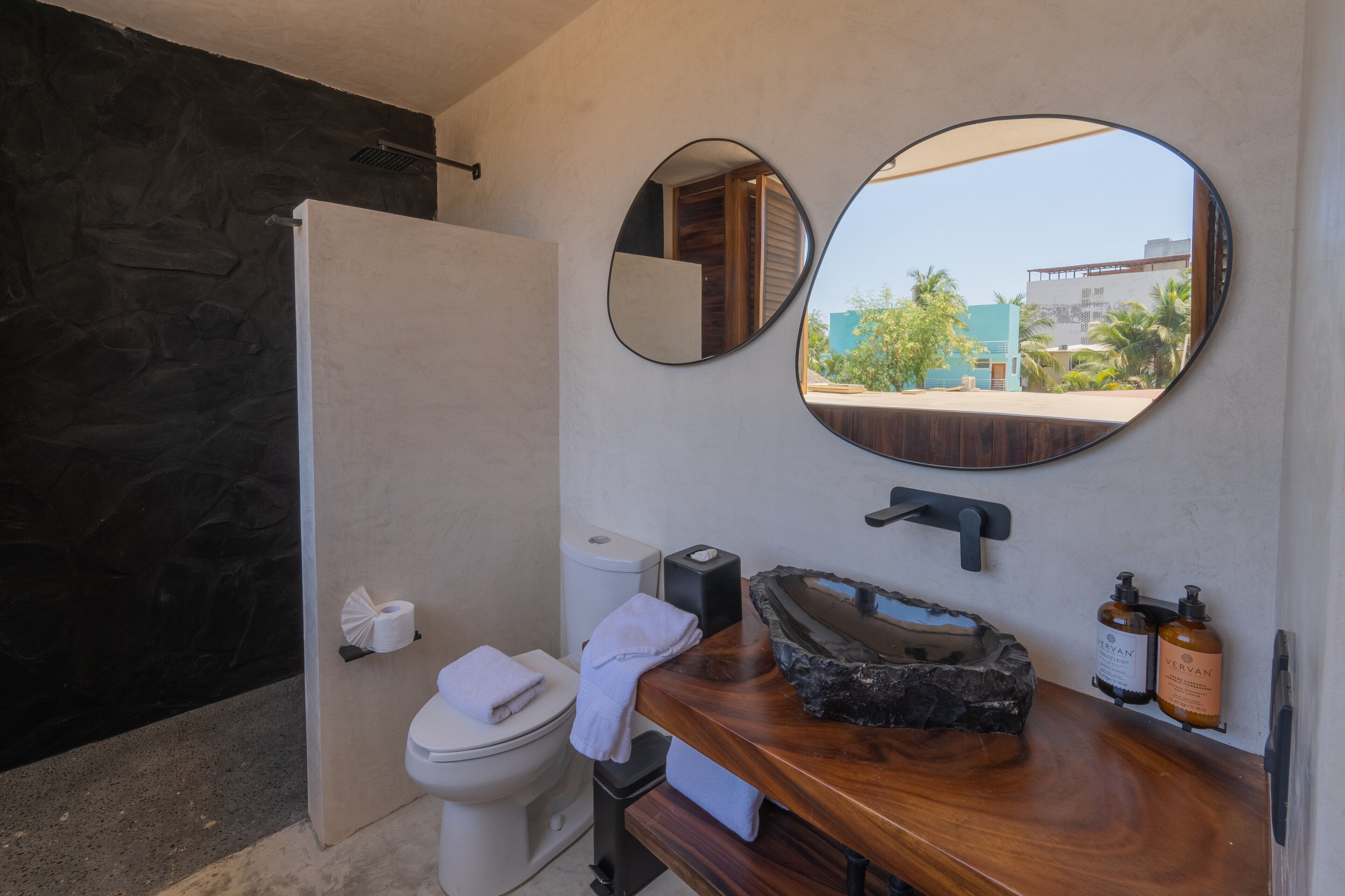 A bathroom with a toilet, sink, and two mirrors.